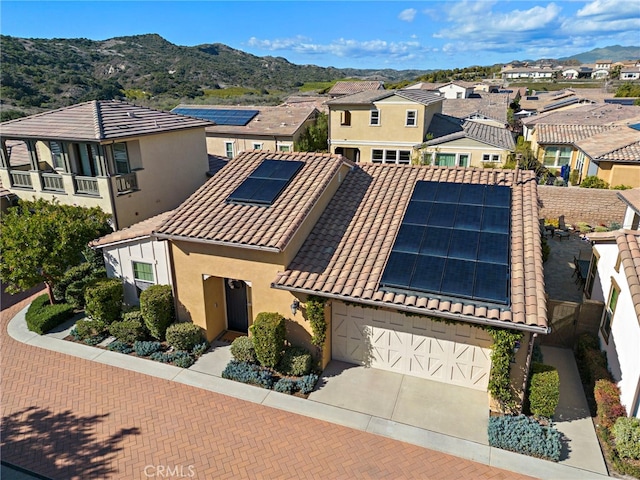 view of front of property featuring a mountain view, a tile roof, driveway, a residential view, and stucco siding