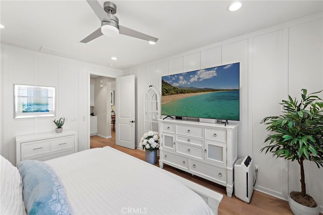 bedroom with ceiling fan, light wood-style floors, recessed lighting, and a decorative wall