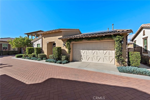 view of front of house with a tiled roof, decorative driveway, an attached garage, and stucco siding