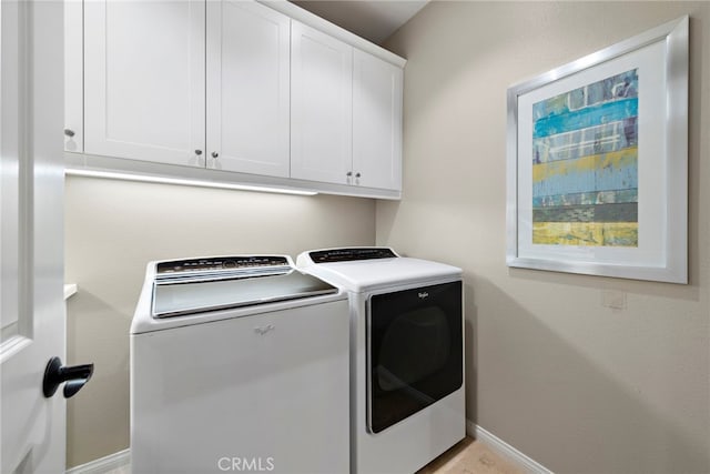 laundry room with cabinet space, baseboards, and washer and clothes dryer