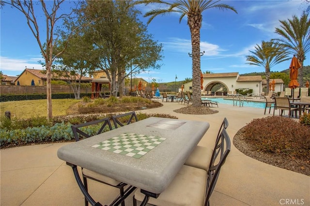 view of home's community with a swimming pool, fence, and a patio