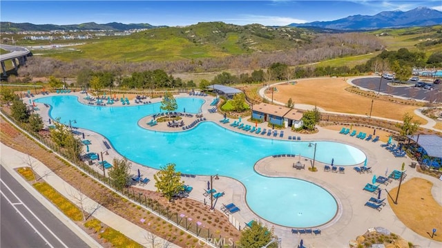 community pool with a patio area, fence, and a mountain view