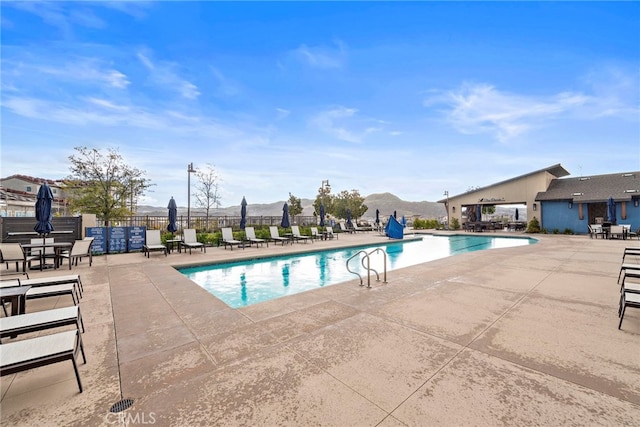 pool featuring a patio, fence, and a mountain view