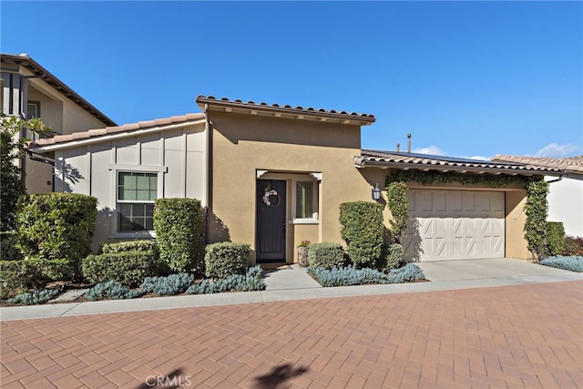 view of front of property featuring a garage, decorative driveway, a tile roof, and stucco siding