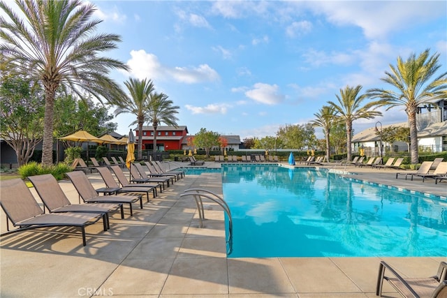 community pool with a patio area and fence