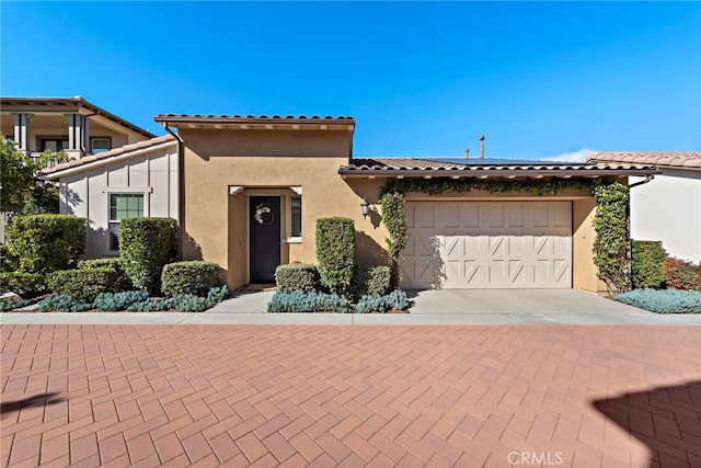 view of front of property with an attached garage, driveway, a tiled roof, and stucco siding