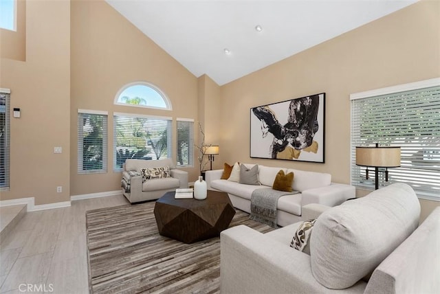 living area featuring light wood-type flooring, baseboards, and high vaulted ceiling