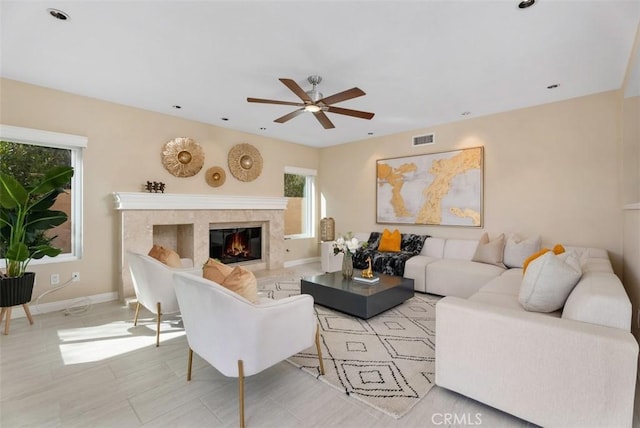 living room with a ceiling fan, baseboards, visible vents, and a tiled fireplace