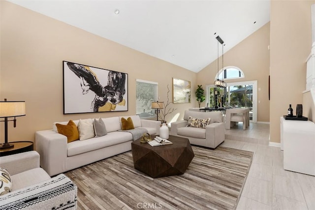 living room featuring high vaulted ceiling and baseboards