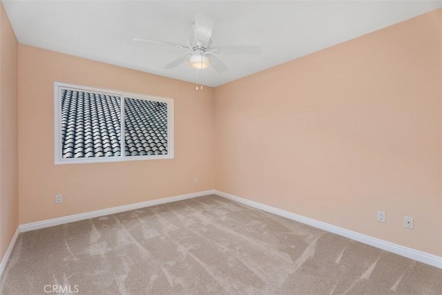 carpeted empty room featuring baseboards and a ceiling fan