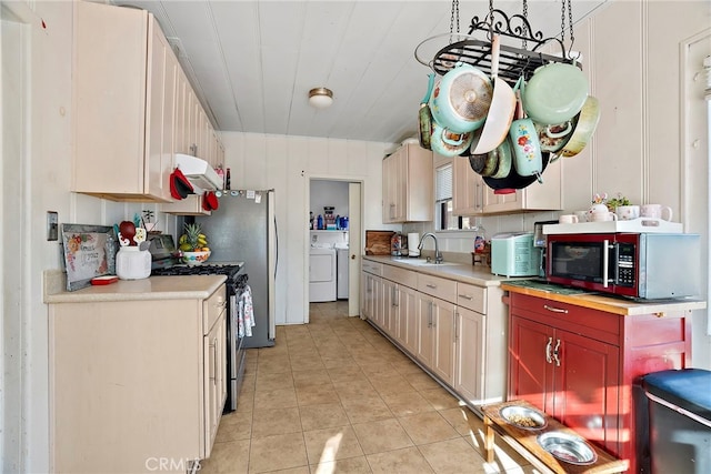 kitchen featuring stainless steel range with gas cooktop, under cabinet range hood, light countertops, and washer and clothes dryer