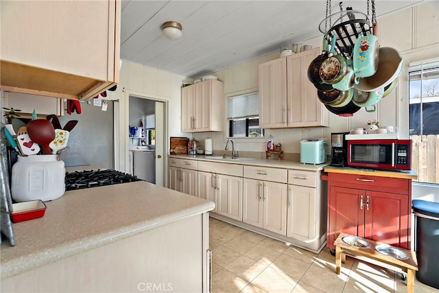 kitchen featuring light tile patterned floors, washer / clothes dryer, light countertops, freestanding refrigerator, and a sink