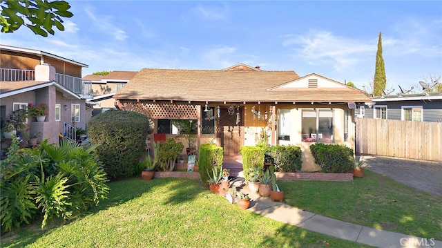 view of front of home featuring a patio area, fence, and a front lawn