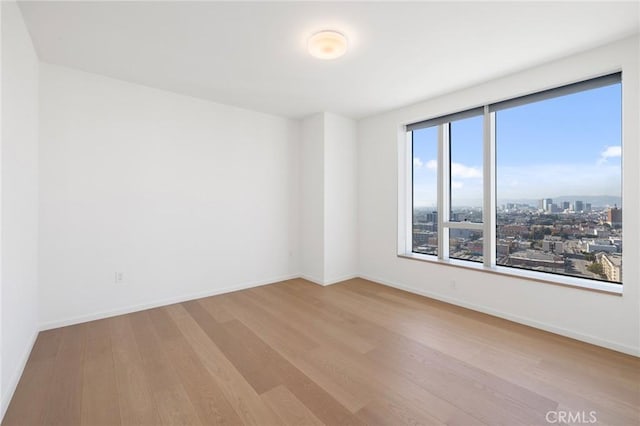 empty room with baseboards, a city view, and wood finished floors