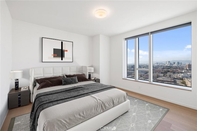 bedroom featuring a view of city, baseboards, and wood finished floors