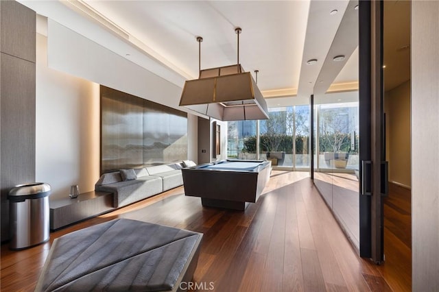 game room with expansive windows, pool table, a tray ceiling, and wood-type flooring