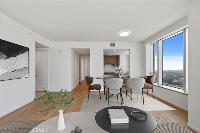 dining room featuring light wood-type flooring, visible vents, and baseboards