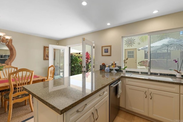 kitchen featuring appliances with stainless steel finishes, dark stone countertops, a sink, and recessed lighting