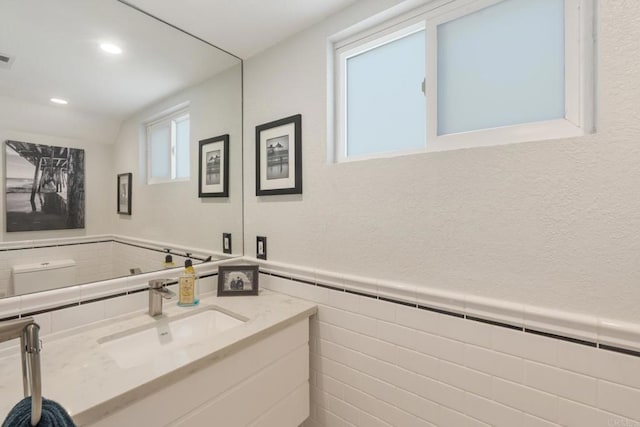 bathroom with wainscoting, a baseboard radiator, vanity, tile walls, and recessed lighting