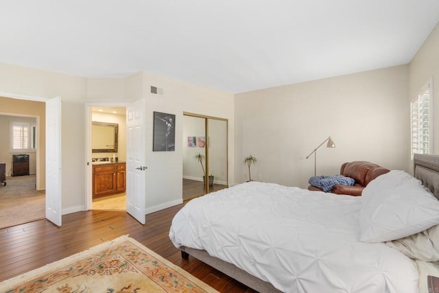 bedroom featuring hardwood / wood-style floors, a closet, visible vents, and baseboards