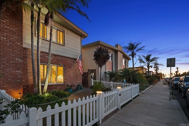 exterior space with brick siding and a fenced front yard