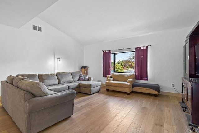 living area with lofted ceiling, light wood-type flooring, and visible vents