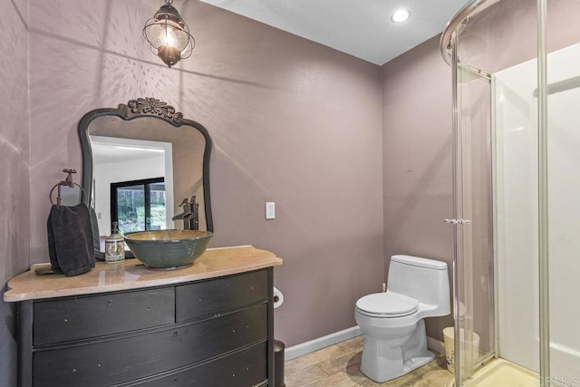 bathroom featuring toilet, a stall shower, vanity, and baseboards