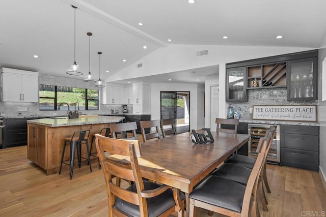 dining space with recessed lighting, visible vents, light wood-style floors, vaulted ceiling, and beverage cooler