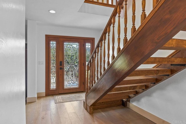 foyer entrance featuring stairs, wood finished floors, and baseboards