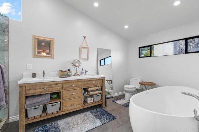 bathroom with double vanity, toilet, a soaking tub, vaulted ceiling, and a sink