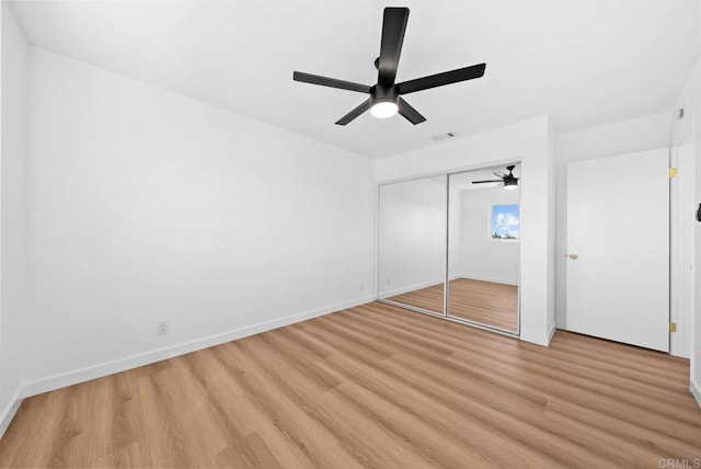 unfurnished bedroom featuring light wood-style floors, a closet, baseboards, and a ceiling fan