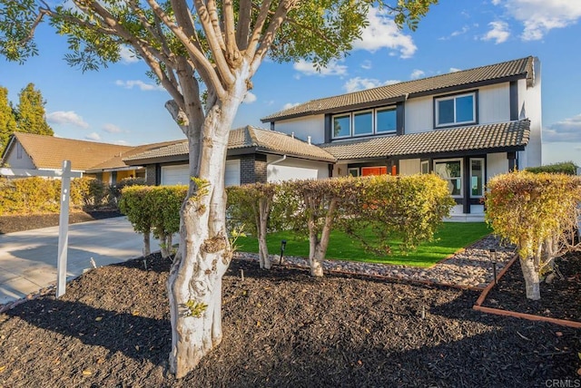 view of front of property with a garage, a tiled roof, a front lawn, and driveway