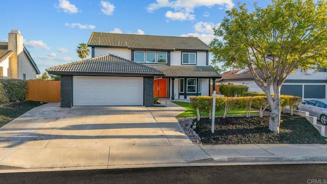 traditional home featuring a tile roof, brick siding, concrete driveway, an attached garage, and fence