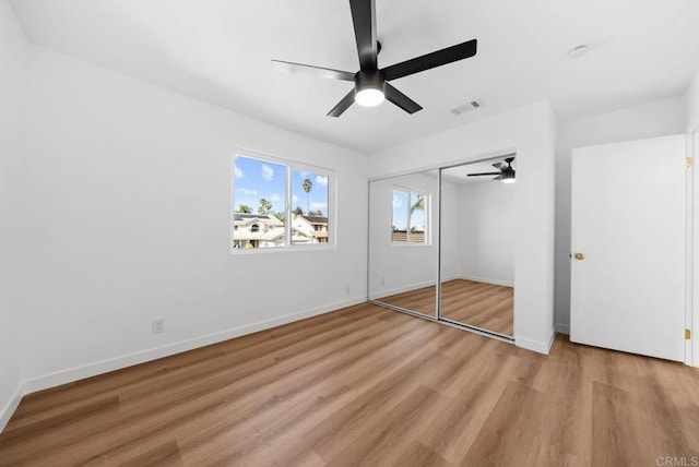 unfurnished bedroom featuring baseboards, visible vents, ceiling fan, light wood-type flooring, and a closet