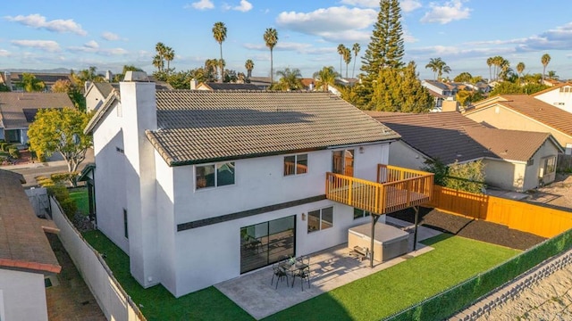 rear view of property with a patio, a chimney, a lawn, a fenced backyard, and a tiled roof