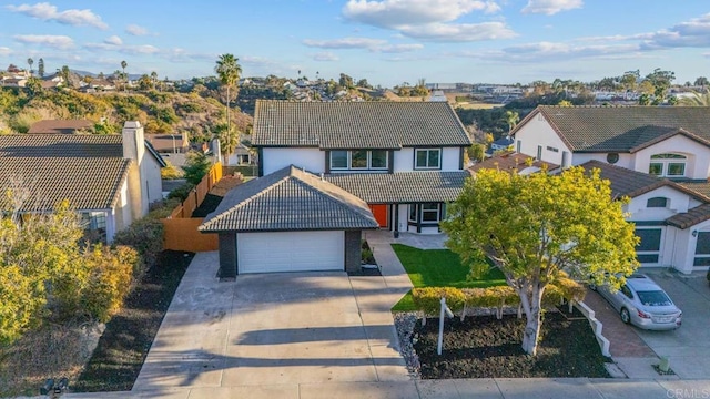 traditional-style home featuring an attached garage, concrete driveway, and a tiled roof