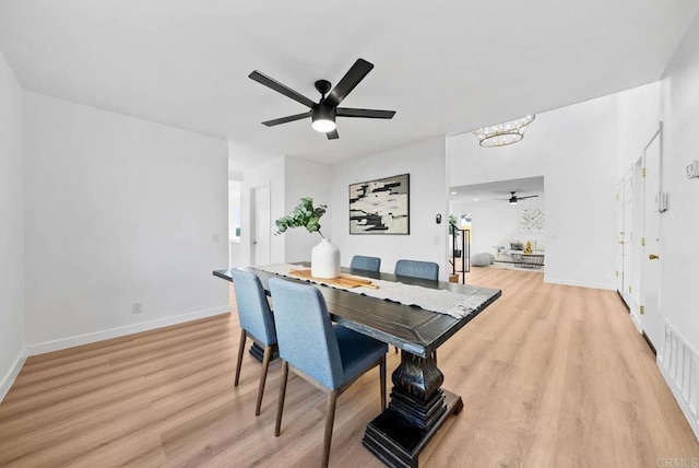 dining area featuring baseboards, visible vents, light wood finished floors, and ceiling fan with notable chandelier