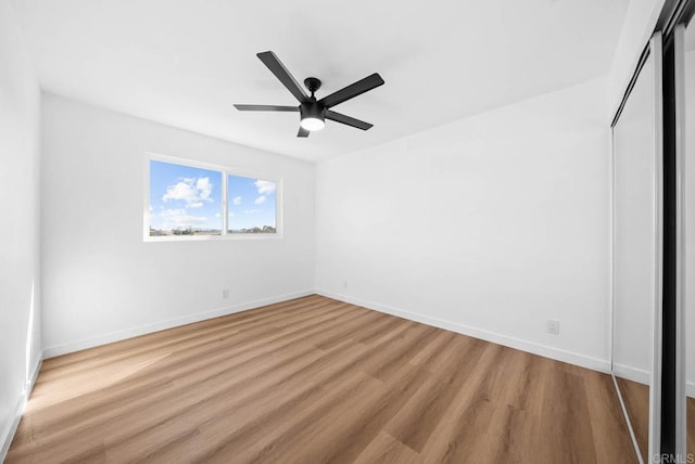 unfurnished bedroom featuring a ceiling fan, a closet, light wood-style flooring, and baseboards