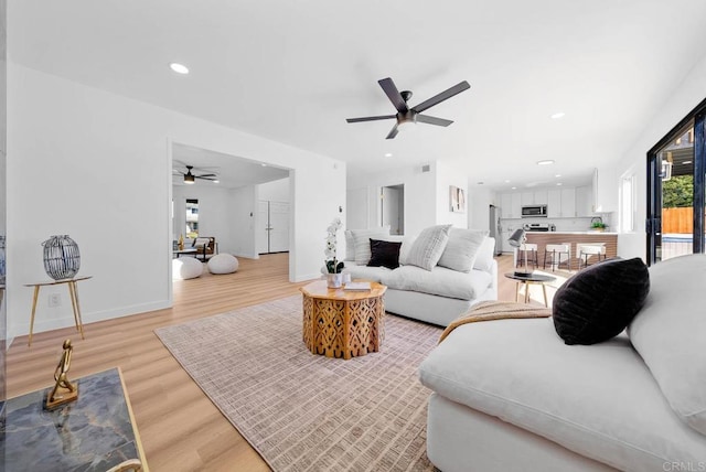 living area featuring baseboards, ceiling fan, light wood-style flooring, and recessed lighting