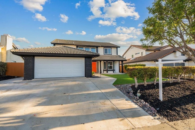 view of front of home with an attached garage, brick siding, fence, concrete driveway, and a tiled roof