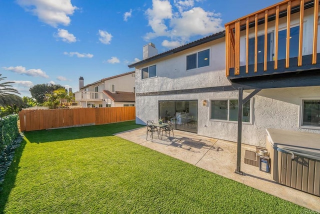 rear view of house featuring a fenced backyard, a yard, stucco siding, a chimney, and a patio area