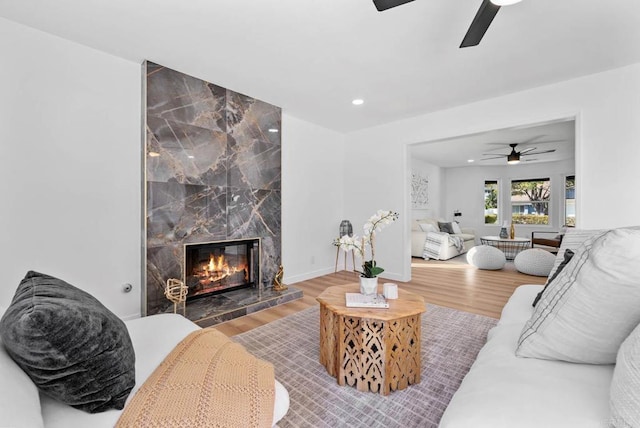 living room with recessed lighting, a premium fireplace, wood finished floors, a ceiling fan, and baseboards