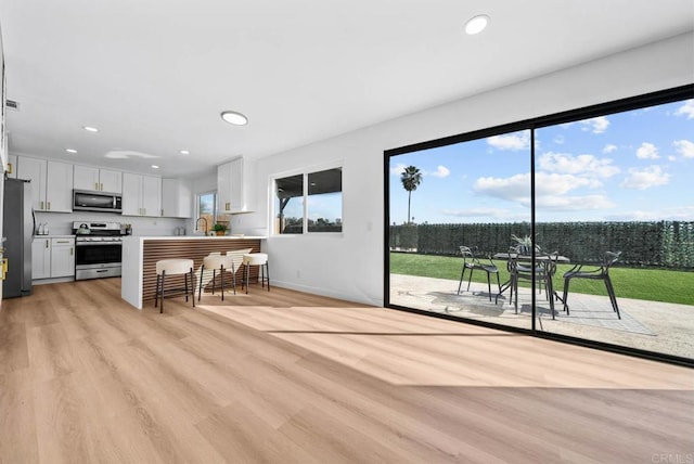 kitchen with recessed lighting, light countertops, light wood-style flooring, appliances with stainless steel finishes, and white cabinets