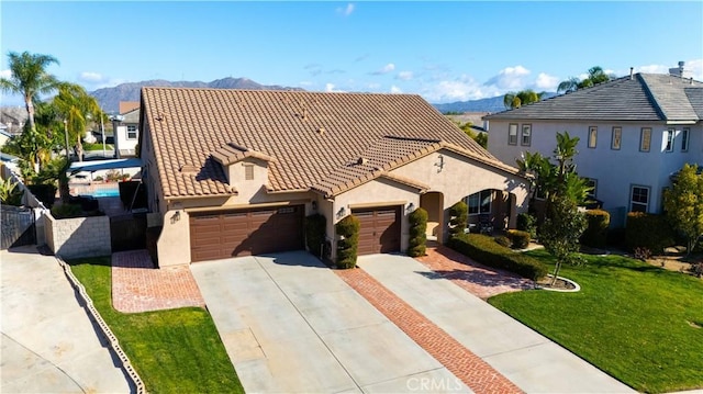 view of front of house with an attached garage, a mountain view, a tiled roof, driveway, and stucco siding