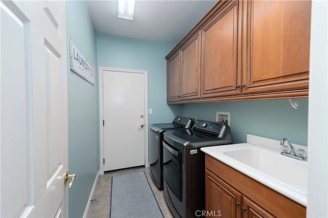 washroom with cabinet space, independent washer and dryer, and a sink