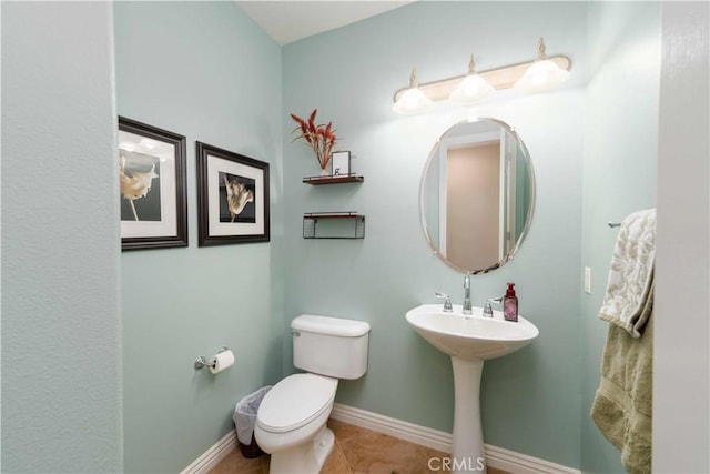 half bathroom featuring tile patterned flooring, toilet, and baseboards