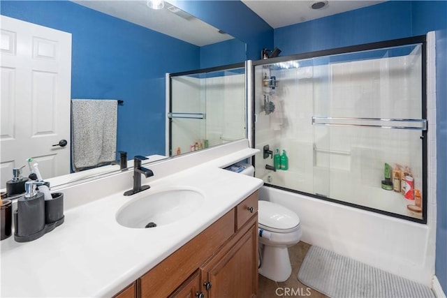 bathroom featuring toilet, shower / bath combination with glass door, and vanity