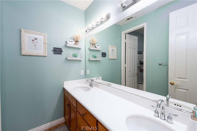 bathroom with double vanity, a sink, visible vents, and baseboards