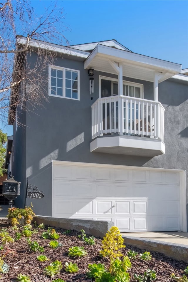 view of front of house with a garage, a balcony, and stucco siding