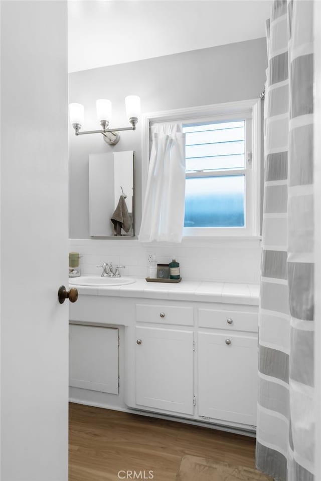 full bath with backsplash, vanity, and wood finished floors